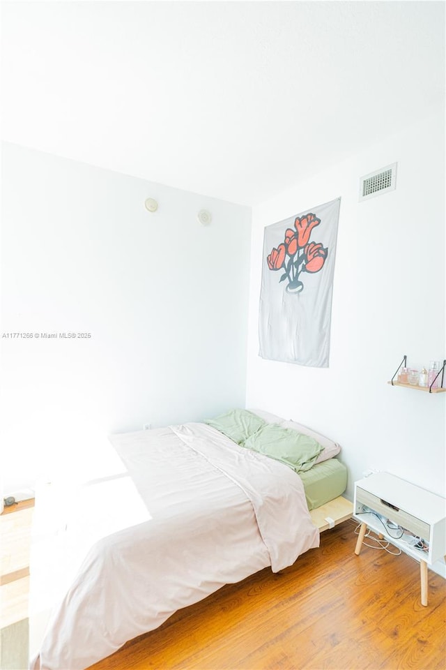 bedroom with visible vents and wood finished floors