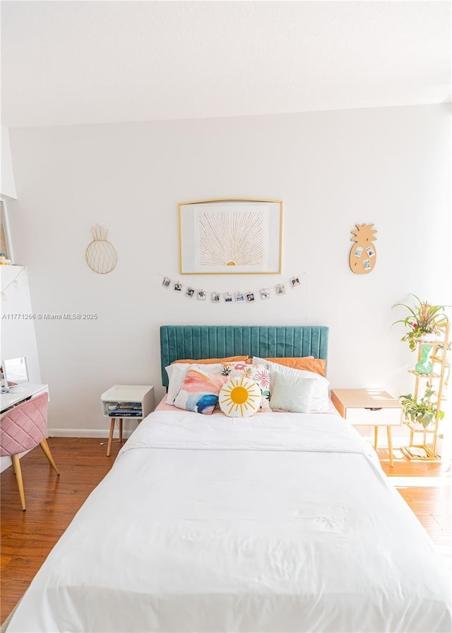 bedroom with baseboards and wood finished floors