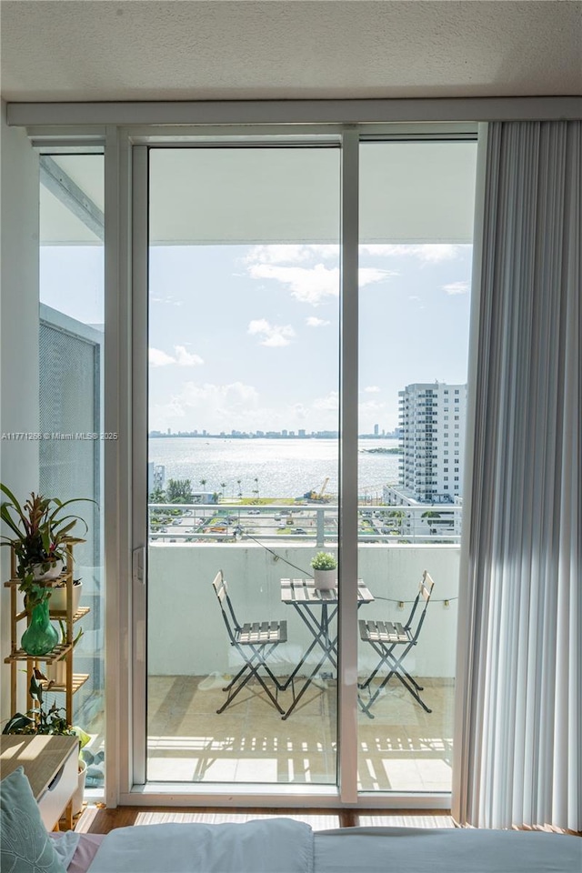 interior space featuring a water view, a textured ceiling, a city view, a wall of windows, and wood finished floors