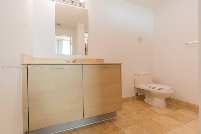 bathroom featuring baseboards, toilet, vanity, and tile patterned floors
