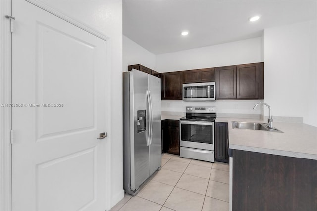 kitchen featuring light countertops, light tile patterned floors, stainless steel appliances, a sink, and dark brown cabinetry