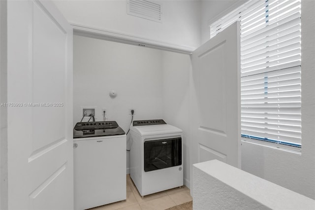 laundry area with light tile patterned floors, washer and dryer, laundry area, and visible vents