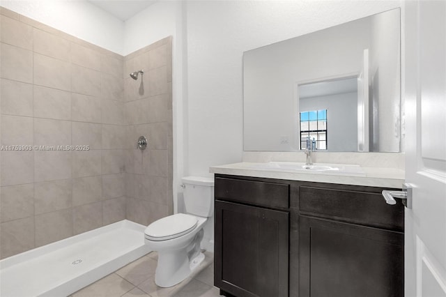 bathroom featuring toilet, vanity, tile patterned floors, and tiled shower