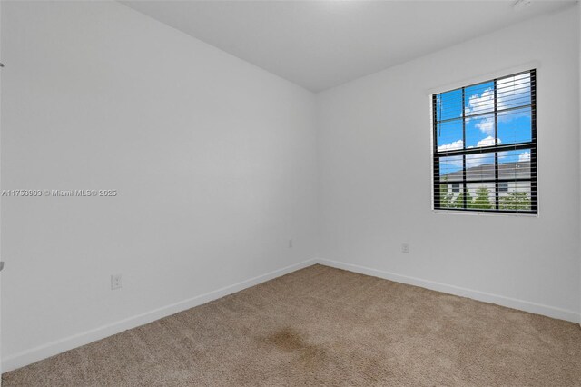 spare room with baseboards and carpet