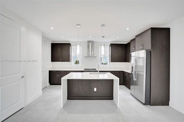 63 NW 4th Ave, Delray Beach, FL 33444 - kitchen featuring light countertops, stainless steel fridge, dark brown cabinets, a sink, and wall chimney range hood