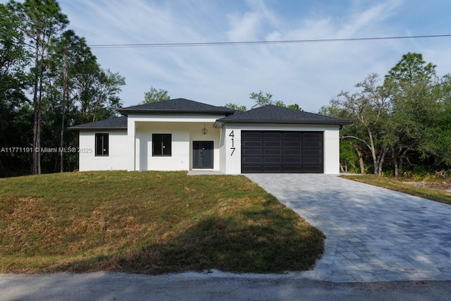 view of front of house with stucco siding, a front yard, decorative driveway, and a garage