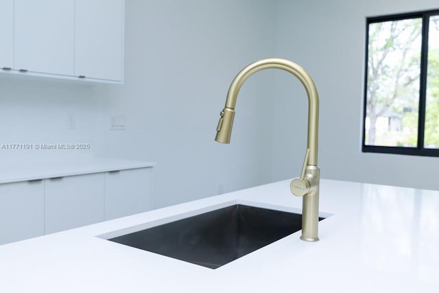 interior details featuring white cabinetry, light countertops, and a sink