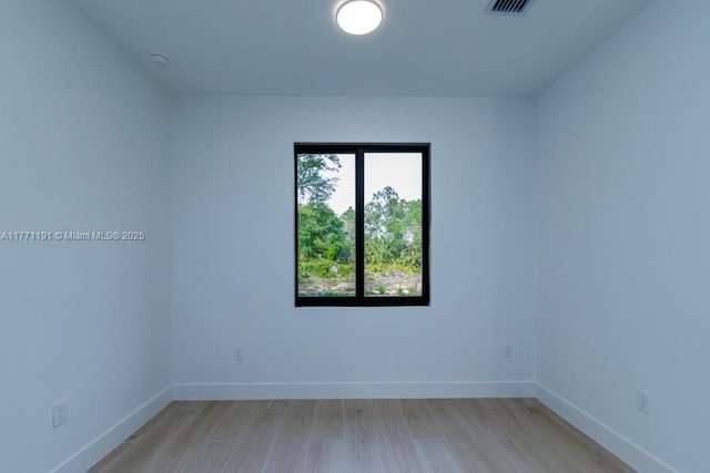 spare room with baseboards, visible vents, and light wood-style floors