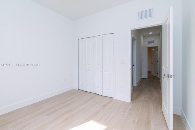 unfurnished bedroom featuring light wood-style flooring, baseboards, and visible vents