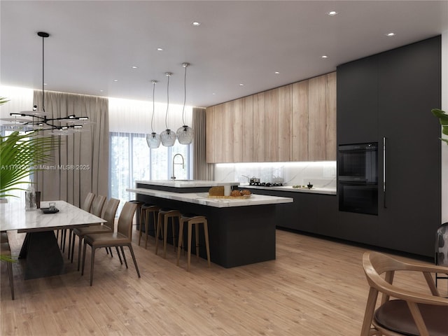 kitchen featuring modern cabinets, a center island with sink, light countertops, and light wood-type flooring