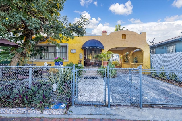 view of front of house with stucco siding, a gate, and a fenced front yard