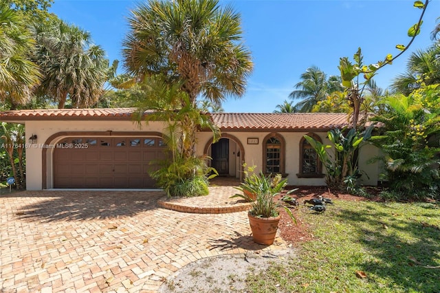 14841 Dade Pine Ave, Miami Lakes, FL 33014 - mediterranean / spanish-style house with stucco siding, an attached garage, decorative driveway, and a tiled roof