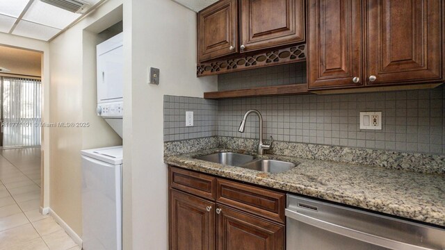 7401 NW 16th St Unit 207, Plantation, FL 33313 - kitchen with stainless steel dishwasher, a sink, stacked washer / dryer, light tile patterned floors, and light stone countertops