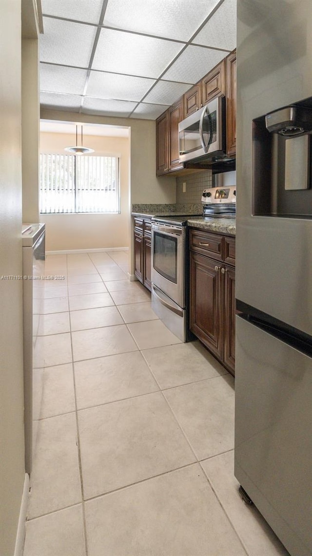 7401 NW 16th St Unit 207, Plantation, FL 33313 - kitchen featuring appliances with stainless steel finishes, light tile patterned floors, baseboards, a paneled ceiling, and dark countertops