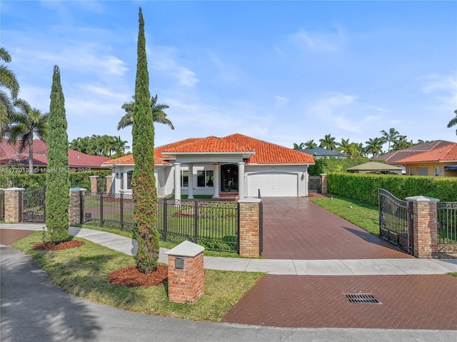 mediterranean / spanish home featuring decorative driveway, an attached garage, a tile roof, a gate, and stucco siding