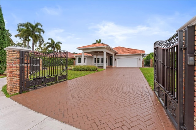 mediterranean / spanish-style home featuring a gate, decorative driveway, an attached garage, a tile roof, and stucco siding
