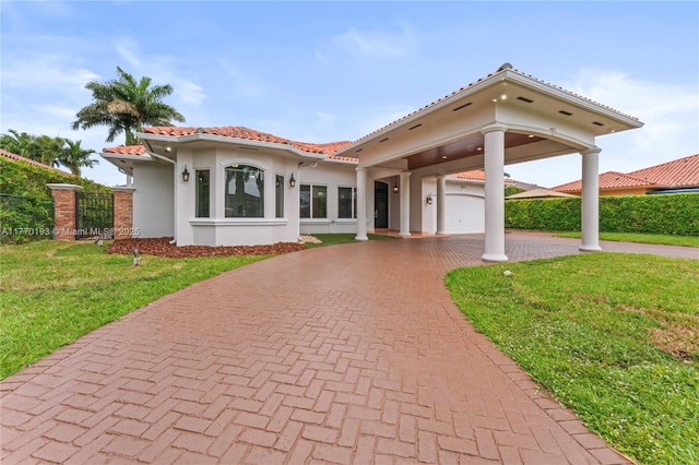 mediterranean / spanish-style home with stucco siding, curved driveway, a tile roof, and a gate