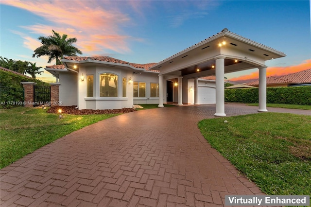 mediterranean / spanish house with a tile roof, stucco siding, decorative driveway, and a front yard