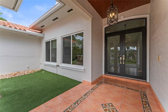 view of exterior entry featuring french doors and stucco siding