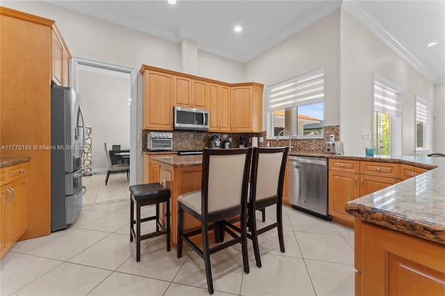 kitchen featuring appliances with stainless steel finishes, crown molding, tasteful backsplash, light tile patterned floors, and dark stone counters