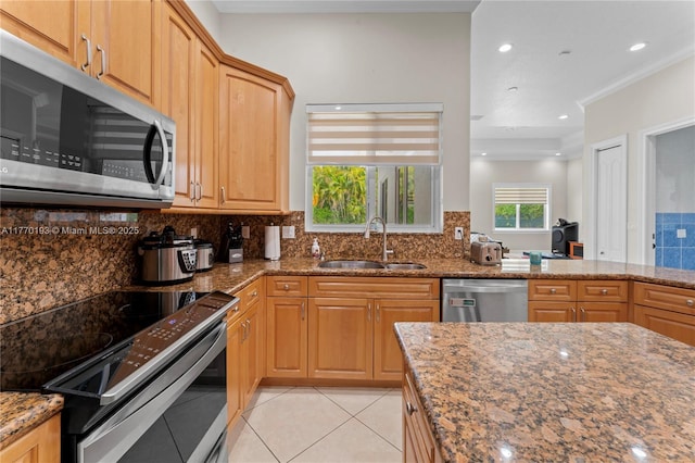 kitchen featuring stainless steel appliances, a sink, light tile patterned floors, dark stone counters, and decorative backsplash