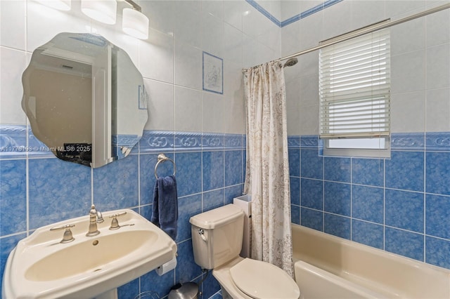 full bath with a sink, tile walls, toilet, and shower / bathtub combination with curtain