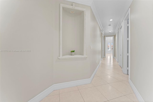 hall featuring crown molding, light tile patterned floors, baseboards, and recessed lighting
