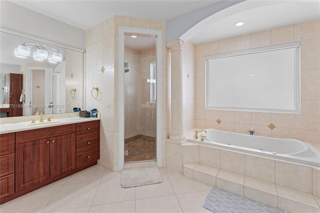 full bathroom featuring a shower stall, a jetted tub, tile patterned flooring, vanity, and ornate columns