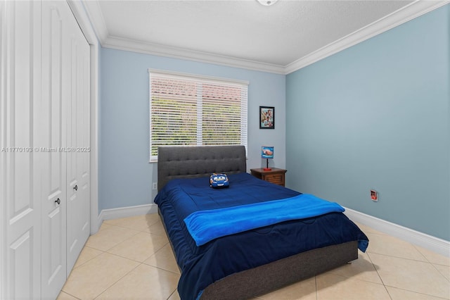 bedroom with crown molding, light tile patterned flooring, baseboards, and a closet