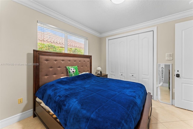 bedroom featuring ornamental molding, light tile patterned flooring, baseboards, and a closet