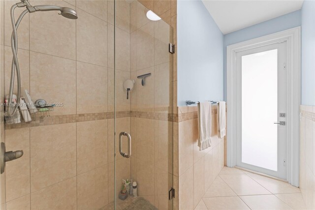 bathroom featuring a stall shower, tile walls, wainscoting, and tile patterned floors