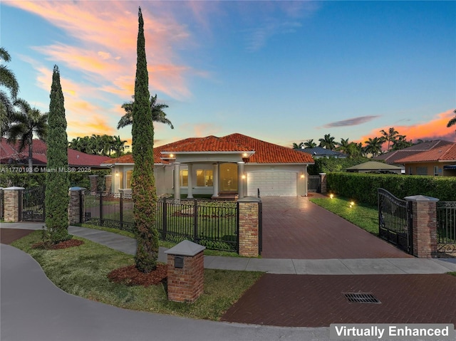 mediterranean / spanish house with a tiled roof, decorative driveway, an attached garage, a gate, and stucco siding