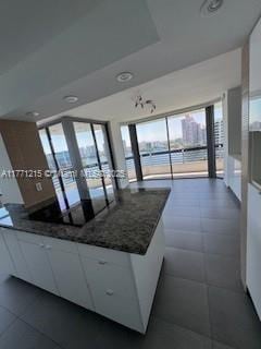 19101 NE Mystic Pointe Dr Unit 1601, Aventura, FL 33180 - kitchen featuring white cabinetry, dark stone countertops, a water view, and black electric stovetop