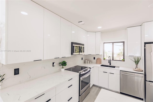 kitchen featuring white cabinetry, appliances with stainless steel finishes, a sink, and modern cabinets