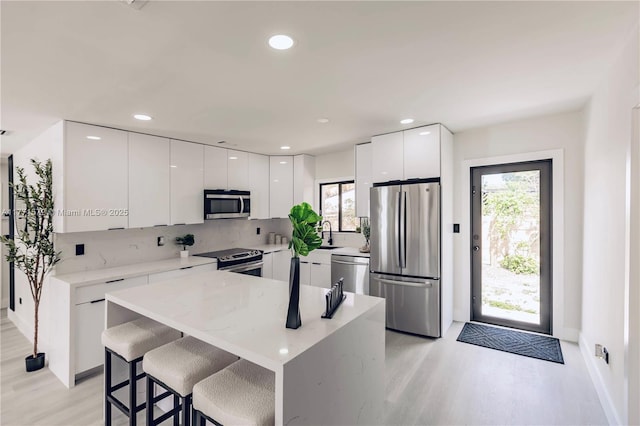 kitchen with white cabinets, plenty of natural light, modern cabinets, stainless steel appliances, and backsplash