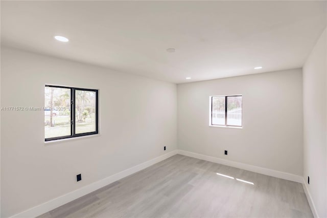 spare room with recessed lighting, light wood finished floors, and baseboards