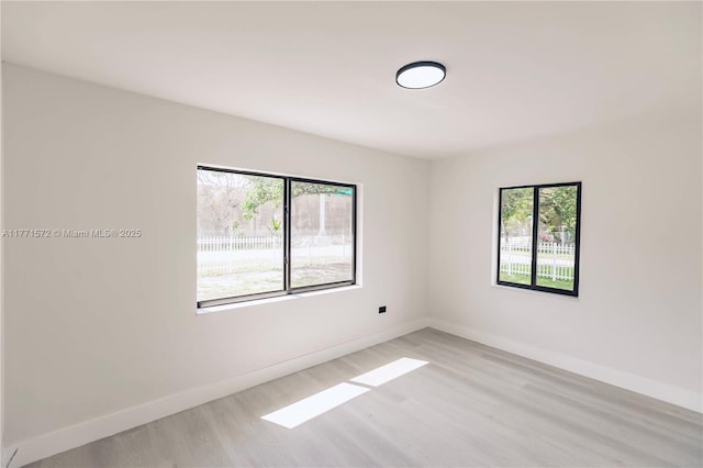 spare room with baseboards and light wood-type flooring