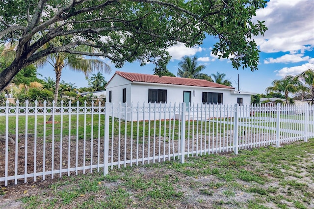 view of front of property featuring a tiled roof, stucco siding, fence, and a front yard