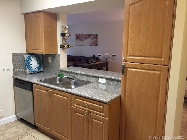 kitchen featuring baseboards, light tile patterned floors, brown cabinetry, dishwasher, and a sink