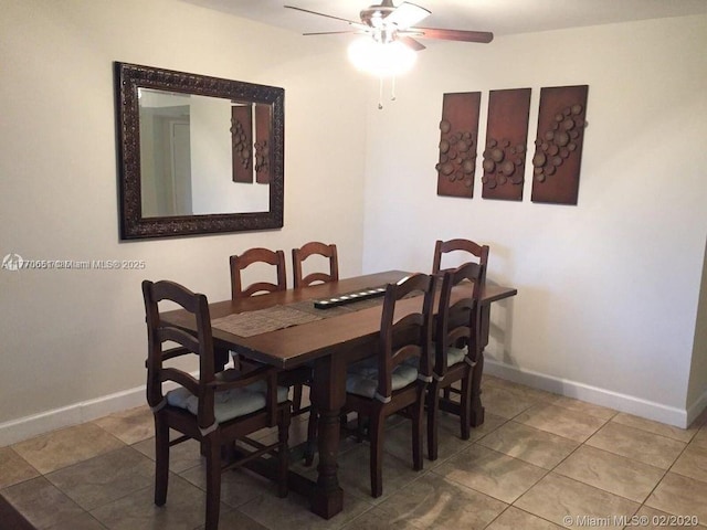 tiled dining space featuring ceiling fan and baseboards