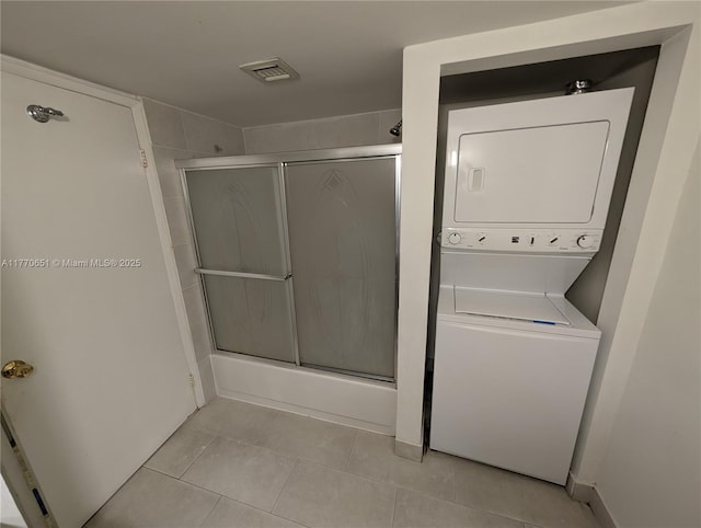 full bathroom with stacked washer and dryer, tile patterned flooring, and visible vents