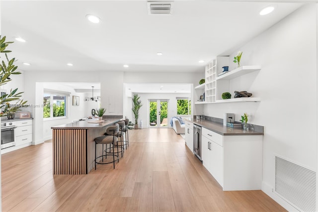 3291 SW 16th Ln, Miami, FL 33145 - kitchen with stainless steel oven, beverage cooler, white cabinets, open shelves, and a kitchen bar