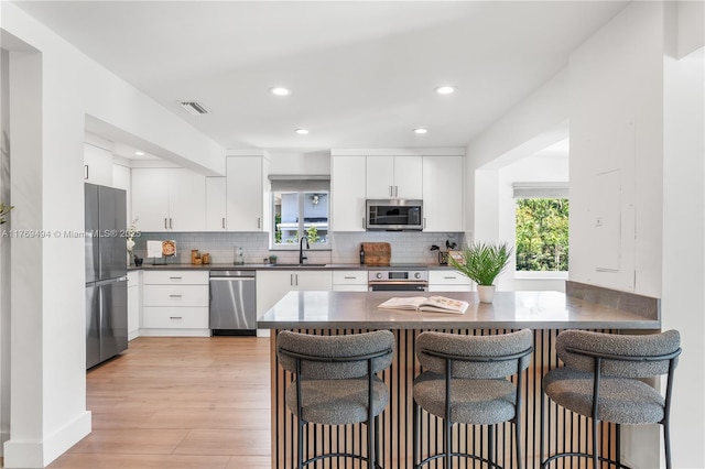 3291 SW 16th Ln, Miami, FL 33145 - kitchen featuring stainless steel appliances, dark countertops, a sink, a kitchen breakfast bar, and decorative backsplash
