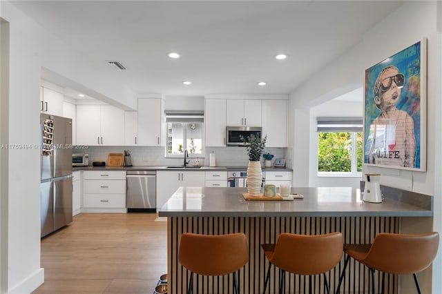 kitchen featuring a sink, appliances with stainless steel finishes, dark countertops, and a breakfast bar