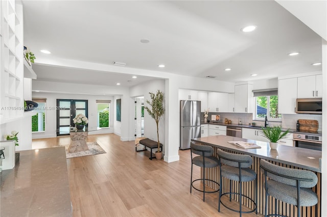 3291 SW 16th Ln, Miami, FL 33145 - kitchen with appliances with stainless steel finishes, dark countertops, a sink, decorative backsplash, and light wood-type flooring