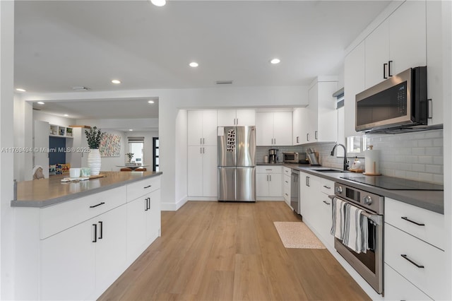 kitchen featuring visible vents, appliances with stainless steel finishes, tasteful backsplash, light wood-type flooring, and a sink