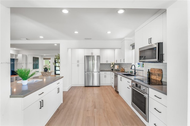 3291 SW 16th Ln, Miami, FL 33145 - kitchen featuring stainless steel appliances, dark countertops, light wood-type flooring, a sink, and tasteful backsplash