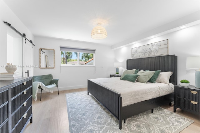 3291 SW 16th Ln, Miami, FL 33145 - bedroom with a barn door, light wood-style floors, and baseboards