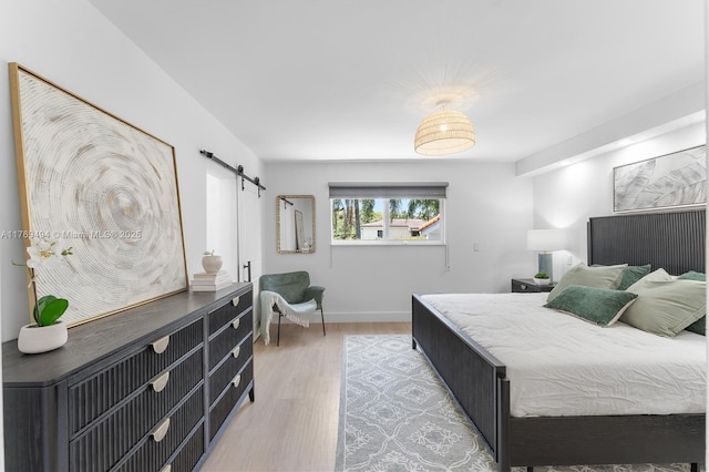3291 SW 16th Ln, Miami, FL 33145 - bedroom with a barn door, light wood-type flooring, and baseboards