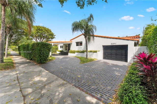 mediterranean / spanish-style home with decorative driveway, a garage, stucco siding, and fence